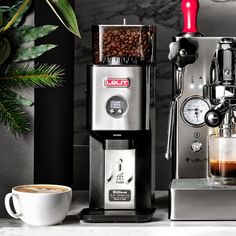 an espresso machine sitting on top of a counter next to a cup of coffee