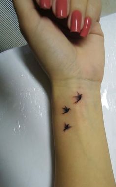 a woman's wrist tattoo with small birds on the left side of her arm