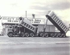 two dump trucks are parked in front of a truck depot