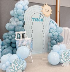 a blue and white party setup with balloons, chairs, and decorations for a baby's first birthday