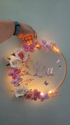 a person holding a light up sign with flowers and butterflies around it that says la