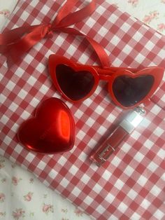 two heart shaped sunglasses and a pen on a checkered tablecloth