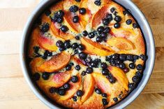 a pie with blueberries and peaches on it is sitting on a wooden table