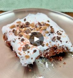 a piece of cake with white frosting and chocolate chips sitting on top of a silver plate