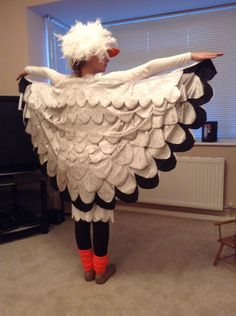 a woman dressed in white and black with an angel wings costume on, standing next to a tv