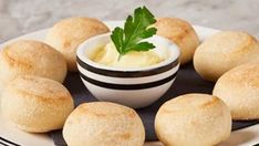 small rolls on a plate with a bowl of cream and parsley in the middle