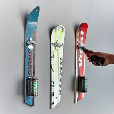 three snowboards are hanging on the wall and one is holding a beer bottle in it