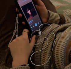 a person sitting on a couch holding a cell phone with ear buds in their hands