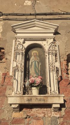 an old building with a statue and flowers in the window