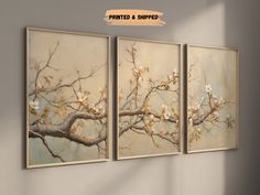 three paintings hanging on the wall next to each other, one with white flowers in it