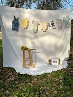 clothes are hung on a line over an easel in front of a white backdrop