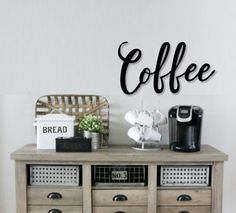 a coffee table with drawers and baskets on it next to a wall mounted sign that says coffee