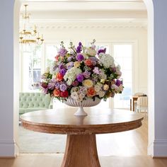 a vase filled with flowers sitting on top of a wooden table in a living room