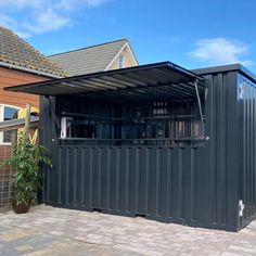 a building made out of shipping containers in front of a brick sidewalk with a potted plant next to it