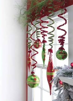 christmas decorations hanging from a window sill in front of a tree with red and green ornaments