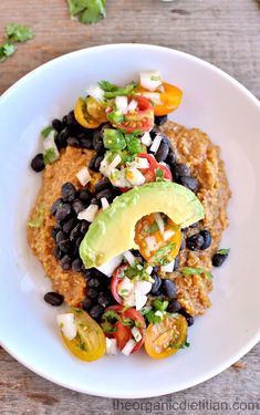 a white plate topped with black beans, avocado and tomatoes