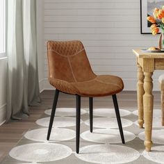 a brown chair sitting on top of a wooden table next to a vase filled with flowers