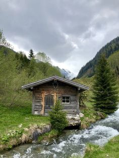 an old log cabin sitting on the side of a river