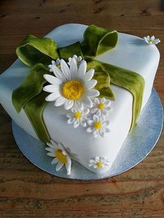 a cake with white flowers and green leaves on it