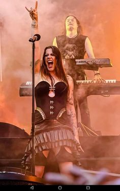 a woman in a corset singing into a microphone while standing next to a keyboard