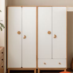 a white and wood armoire in a room with an orange chair next to it