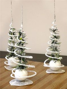 two white christmas trees sitting on top of a wooden table