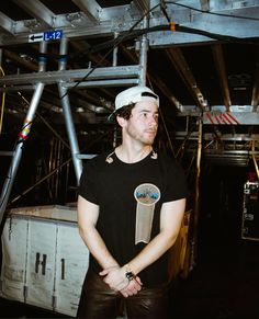 a man in a black shirt and white hat standing with his hands on his hips