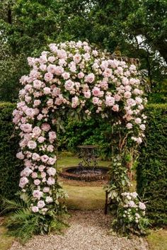 an arch covered in pink flowers and greenery