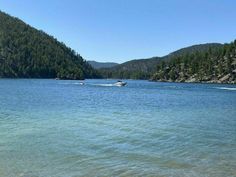 there is a boat that is in the water and some trees on the hill behind it