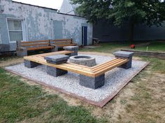 a fire pit sitting on top of a cement slab next to a wooden bench in a yard