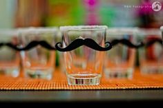 several shot glasses sitting on top of a table with a moustache in the middle