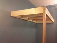 a loft bed with a wooden frame in a small room next to a blue wall