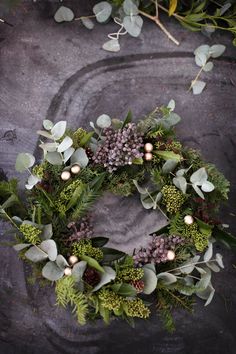 a wreath with greenery and lights on it