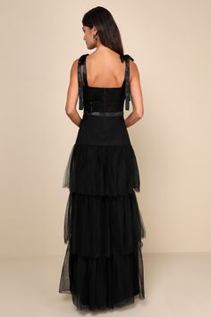 Prepare to enchant everyone with a head-turning look like the Lulus Enticing Mystique Black Tulle Tie-Strap Tiered Maxi Dress! This memorable dress has a lightweight, sheer tulle overlay that falls from tying satin straps into a straight neckline and a fitted bodice with sheer panels and corset-inspired seam details. The high, banded satin waist sits atop a dramatic tiered skirt that finishes at a sweeping maxi hem. Hidden zipper/clasp at back. Fit: This garment fits true to size. Length: Floor Black Tie Wedding Guest Dress Fall, Wedding Guest Dress Fall, Holiday Formal Dresses, Black Tie Wedding Guest Dress, Black Holiday Dress, Black Tie Wedding Guest, Black Tulle Dress, Anniversary Dress, Black Tie Wedding Guests