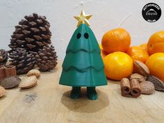 a small green christmas tree sitting next to oranges and nuts on a wooden table