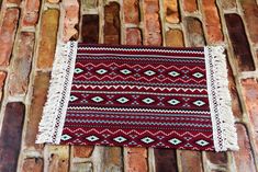 a red and white rug sitting on top of a brick floor