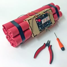 an electronic device is wrapped in red paper and some tools are laying on the table