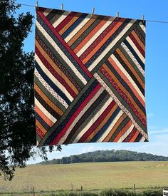 a quilt hanging from a clothes line in a field