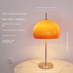 an orange lamp sitting on top of a white table next to a light fixture with measurements