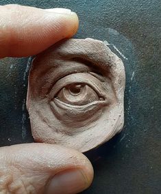 a hand holding a piece of clay that looks like an eye in the middle of it