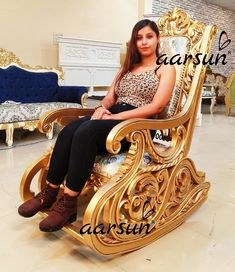 a woman is sitting on a gold chair