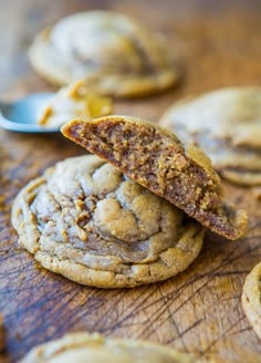 a cookie with a bite taken out of it sitting on a wooden table next to other cookies