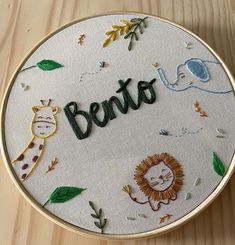 a close up of a embroidery on a wooden surface with the word bento written in it