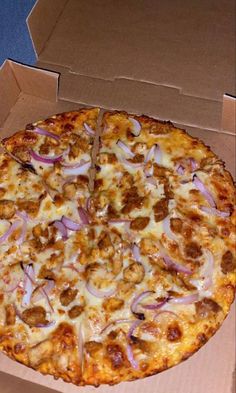 a pizza in a box with onions and meat toppings on the top is ready to be eaten