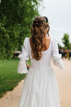 a woman in a white dress walking down a path with her back to the camera