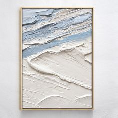 an abstract painting with white and blue colors on the wall above it is a gold frame