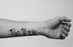 a person's arm with a small city tattoo on the left side of their arm