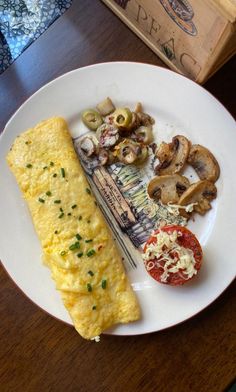 an omelet is on a plate with mushrooms, tomatoes and other food items