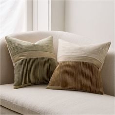 two pillows sitting on top of a white couch