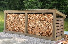 logs stacked on top of each other in front of a wooden structure with gravel underneath